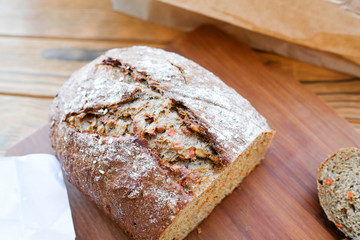 Bread, cut piece, paper bag. Homemade baked bread with grains and carrots