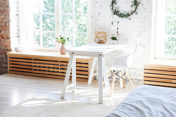 Stylish loft modern home office interior. Spacious design apartment with light walls large windows and writing desk. Clean modern decoration with elegant furniture in minimalist Scandinavian style.