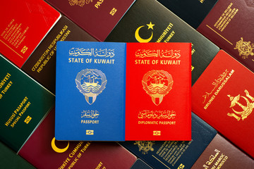 Kuwait diplomatic and national passports on the background of various documents of the world.