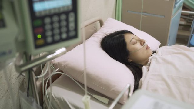 high angle view woman cancer patient is sleeping in ward after operation. asian recovering lady is resting in bed alone in hospital. illness and hospitalization concept