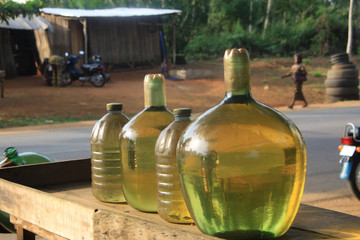 butelki i baniaki z benzyną  na drewnianym stoliku przy drodze wystawione na sprzedaż na afrykańskiej prowincji