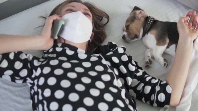 A woman in quarantine is in bed with a cute puppy beagle.