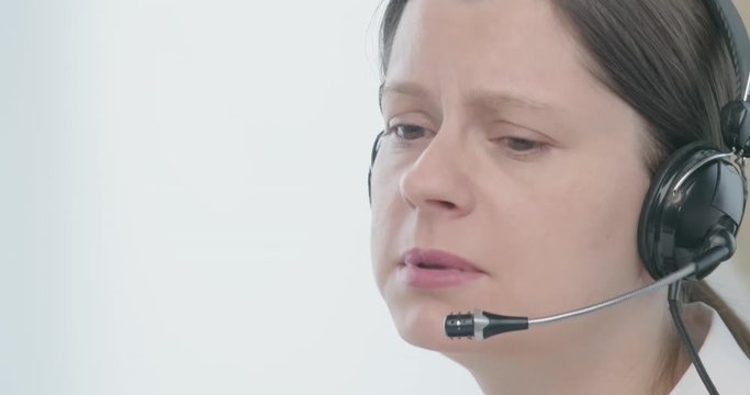 Woman in headset talking to a client with sad face to solve problems.
