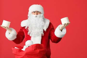 Santa Claus with toilet paper in bag on color background. Concept of coronavirus epidemic