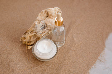 Fototapeta na wymiar Caring cosmetics in an oyster shell on the sand. Eco-friendly organic cosmetics.