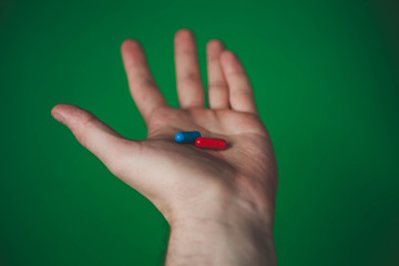 red and blue tablet in a man hand on a green background