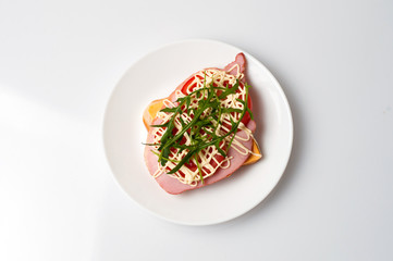 Sandwich of bread for toast, sturgeon, tomatoes, arugula, cheese and mayonnaise on a white plate in the view from the top flat lay, copy space
