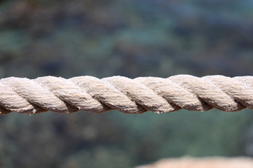 strong powerful rope holding large loads against a blue blurred sea