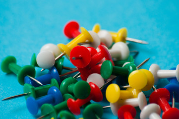 Multicolored push pins on a blue background macro closeup
