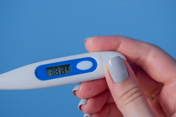 Woman hands holding white digital medical thermometer with high temperature - close up view, selective focus. Healthcare, measurement, disease, infection, coronavirus concept