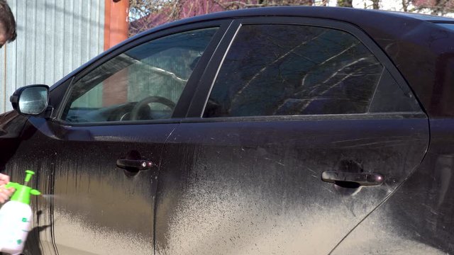 A man puts foam on a car to remove dirt. Special detergent for car wash. Washes a car in front of the house.
