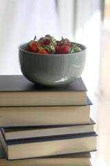 Stack of books and bowl of fresh strawberries. Selective focus. 