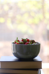 Stack of books and bowl of fresh strawberries. Selective focus. 