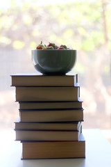 Stack of books and bowl of fresh strawberries. Selective focus. 