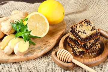 honey in honeycombs on a wooden plate and honey with nuts with lemon and ginger in rustic style on a wooden background. Close-up