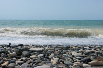 A small storm three or four points at sea, the wave hits the shore with a large pebble.