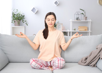 Portrait of beautiful young woman meditating at home