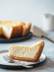 Plate with piece of cheesecake on tabletop. Classic homemade cheesecake with Shallow DOF. Vertical. Copy space for text. - obrazy, fototapety, plakaty