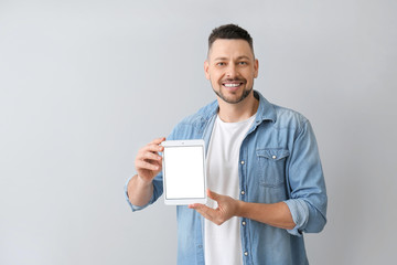 Handsome man with tablet computer on grey background