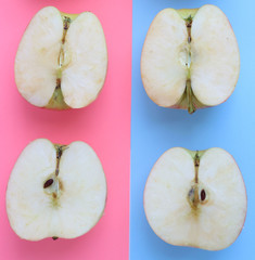 halves of apples lie on a blue and pink paper background, close-up. Freshness, vitamins, fruits in...
