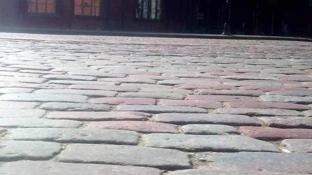 slide motion along stone pavement in perspective in low angle. closeup cobblestone pavement.