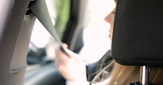the hand of a girl fastens the seatbelt in the car.