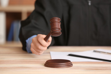 Male judge with gavel at table in office, closeup