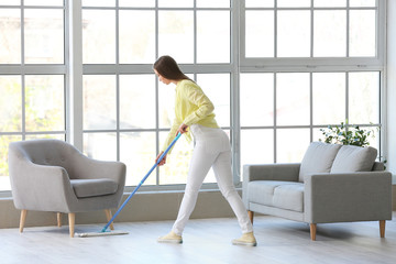 Fototapeta na wymiar Young woman mopping floor in room