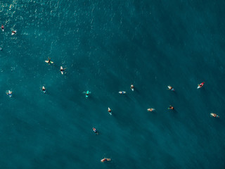 Aerial view of a lot surfers in blue sea. Top view