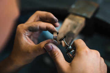 Master goldsmith while working on jewelry on the of work table.