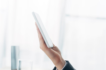 Cropped view of man holding smartphone with blank screen in hand