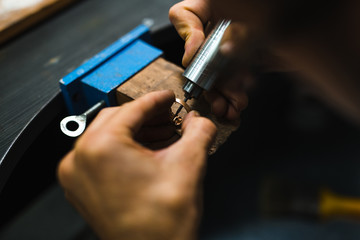 Master goldsmith while working on jewelry on the of work table.