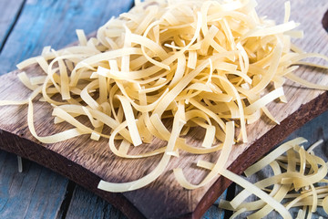 Dry pasta on a cutting board on a background of blue boards.