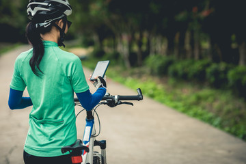 Cyclist use smartphone for navigation when riding mountain bike on forest trail