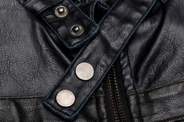 close up of a black leather vintage motorcycle jacket, zipper and press studs.