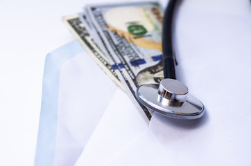 Stethoscope and syringe, Dollars money bills spread in a white paper envelope on white background. Health care cost concept