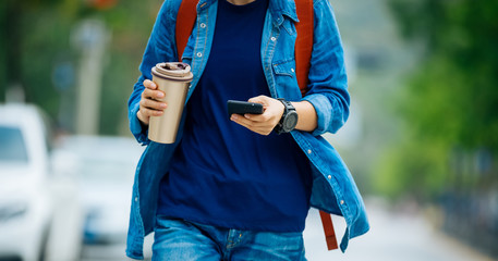People use mobile phone walking with coffee cup in hand
