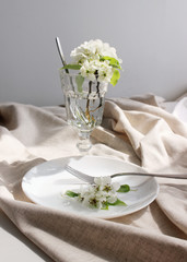 
bright interior. white plate on the table with folds of linen. spring pear flowers on a plate. table decor, interior details. close-up.