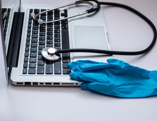 Stethoscope and blue medical glove on laptop, and beautiful twilight sun,Health care cost concept, copy space