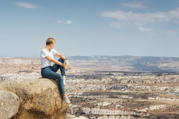 Fototapeta na wymiar Traveler young woman sitting on a rock on mountain top with beautiful view under horizon, adventure