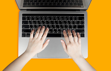 A woman's hand placed on a laptop and an orange background.
