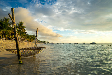 Obraz premium A hammock on the beach against a background of clouds, the ocean and an incredible sunset. Mauritius Island