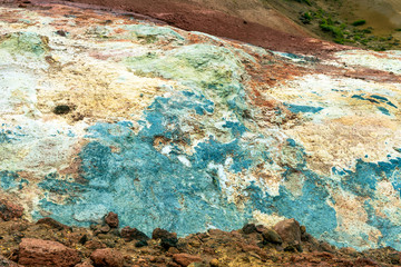 Multi colored bubbling hot pool and colorful soil , rocks and dirt in geothermal and volcanic area in Iceland. Texture and pattern concept.