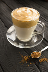Dalgona coffee in the glass cup in the black wooden  background. Location vertical.