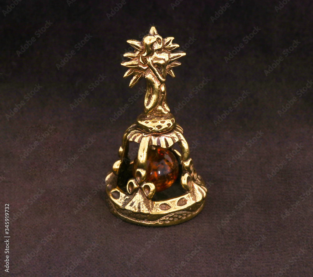 Wall mural Amber souvenir. A miniature metal bell in the form of a zodiac sign 