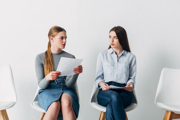 Stressed employee looking at young woman with resume in office
