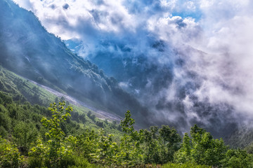 Heavy fog and clouds in mountain gorge in the summer or spring. A layer of melting snow in the...