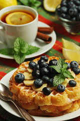 Belgian waffles with blueberry and a cup of tea with lemon