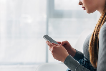 Cropped view of applicant using smartphone with blank screen in office