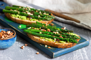 Vegan whole grain bread sandwich with asparagus, pea puree, nuts and soy sauce.